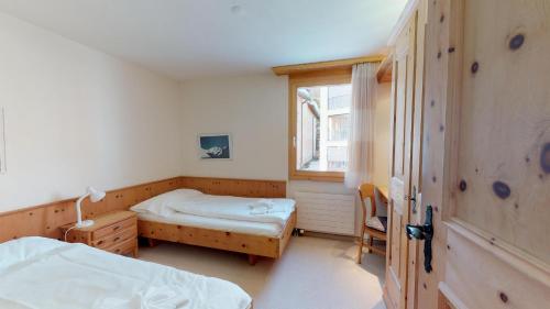 a bedroom with two beds and a window at Pizzet A6 in Silvaplana