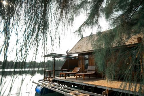 ein Haus mit zwei Stühlen und einem Tisch auf einem Dock in der Unterkunft Tara Beach Resort Udonthani in Udon Thani