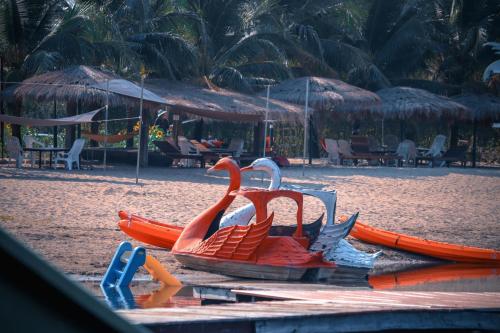 a fake swan on a beach with chairs and tables at Tara Beach Resort Udonthani in Udon Thani