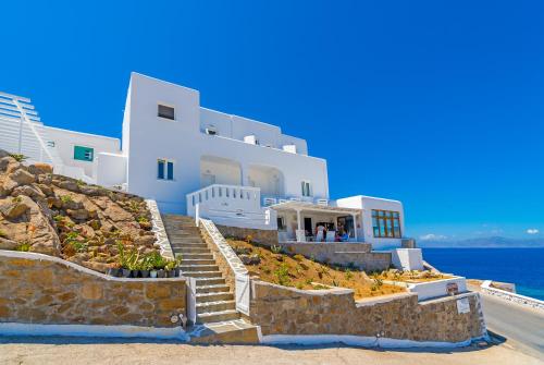 a building on a hill with stairs next to the ocean at Cape Mykonos in Mýkonos City