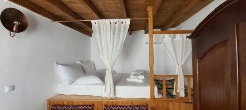 a bedroom with a bunk bed with white curtains at Traditional house in Asfendiou in Kos