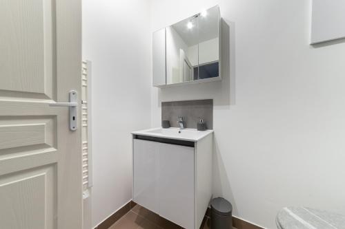 W łazience znajduje się biała umywalka i lustro. w obiekcie Le Borie climatisé w mieście Arles