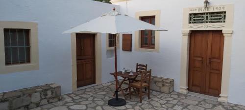 a table and chairs under an umbrella outside of a building at Traditional house in Asfendiou in Kos Town
