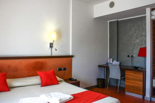 a bedroom with a bed with red pillows and a desk at Hotel Bed&Business in San Giovanni Teatino