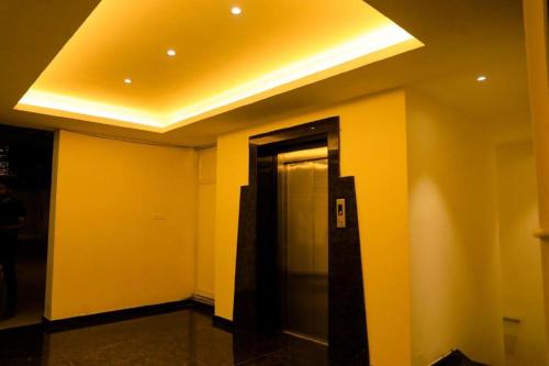 a hallway with yellow walls and a elevator at Laya Regency in Mayiladuthurai
