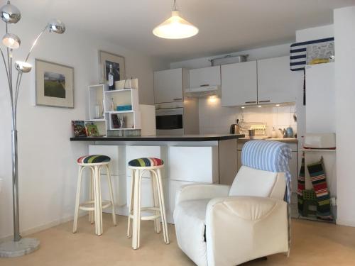 une cuisine avec des placards blancs, 2 tabourets et un comptoir dans l'établissement Duplex T4 idéalement situé entre la place du marché et le bord de mer, à Le Touquet-Paris-Plage
