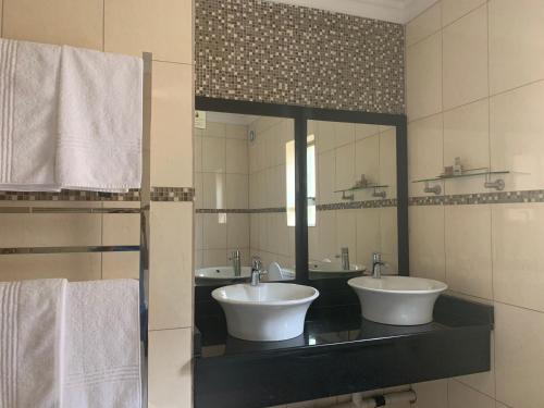 un bagno con due lavandini e un grande specchio di Royal Hotel a Polokwane