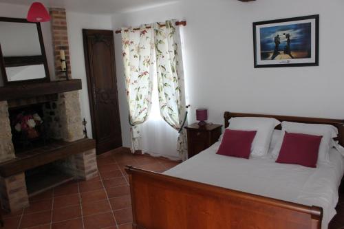 a bedroom with a bed with red pillows and a fireplace at Au Temps Retrouvé in Courcelles