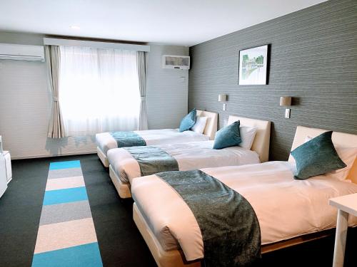 軽井沢町にあるソラホテル軽井沢アウトレットのベッド3台と窓が備わるホテルルームです。