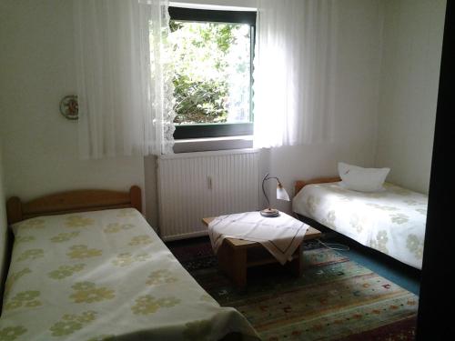 a room with two beds and a window and a table at Seebach Vermietung in Weisendorf