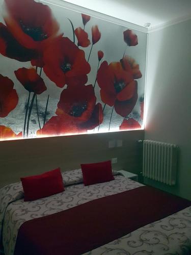 a bedroom with a bed and a painting of red flowers at Albergo Paradiso in Maccagno con Pino e Veddasca