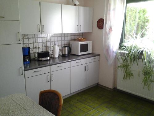 a kitchen with white cabinets and a microwave at Seebach Vermietung in Weisendorf