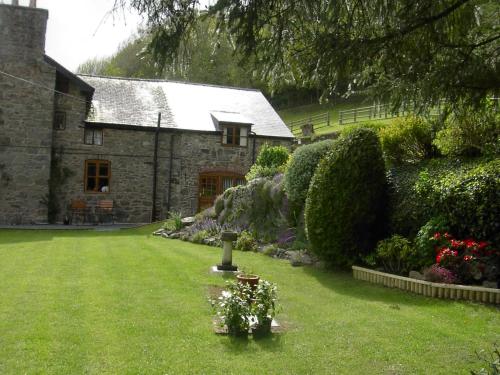 una vecchia casa in pietra con un cortile fiorito di TAN Y GRAIG a Meifod
