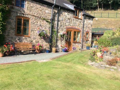 a stone house with a bench in front of it at TAN Y GRAIG in Meifod