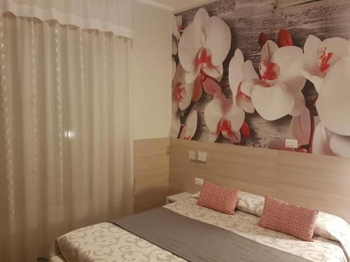 a bedroom with a bed and a painting of flowers at Albergo Paradiso in Maccagno con Pino e Veddasca