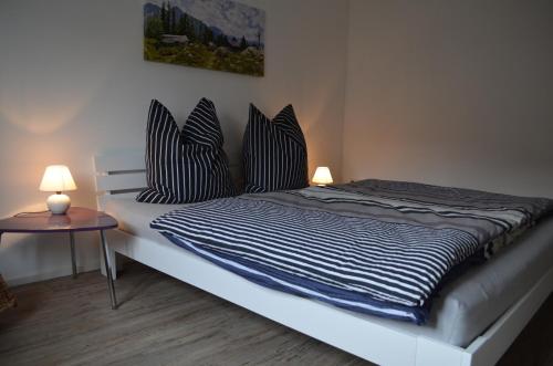 a bed with black and white pillows and a table at Ferienwohnung 2 - Kayserstube in Ainring