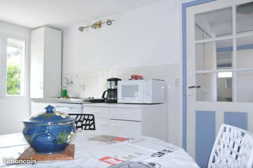 a kitchen with a table with a blue vase on it at CENTRE CHATELAILLON GRAND T2** AVEC COUR 100mPLAGE in Châtelaillon-Plage