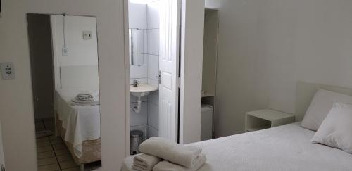 uma pequena casa de banho branca com uma cama e um lavatório. em Hospedagem São Francisco em São Luís
