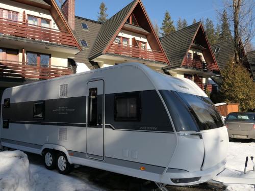 a silver and black caravan parked in front of a house at Kamping u Łukasza in Zakopane