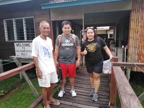 a group of three people standing on a wooden walkway at AA Homestay in Mulu