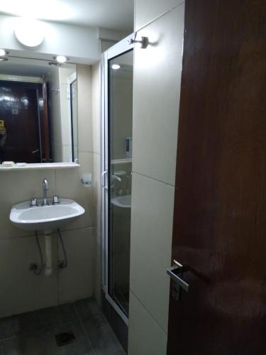 a bathroom with a sink and a glass shower door at Hotel Garden in San Miguel de Tucumán