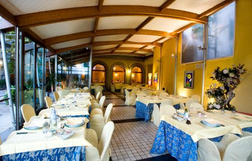 Hotel Corallo في مونتيكاتيني تيرمي: مطعم بطاولات بيضاء وكراسي بيضاء