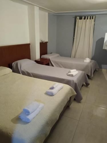 a hotel room with three beds with towels on them at Hotel Garden in San Miguel de Tucumán