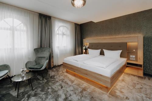 ein Schlafzimmer mit einem großen Bett und einem Stuhl in der Unterkunft Hotel Schwarzer Adler Stendal in Stendal