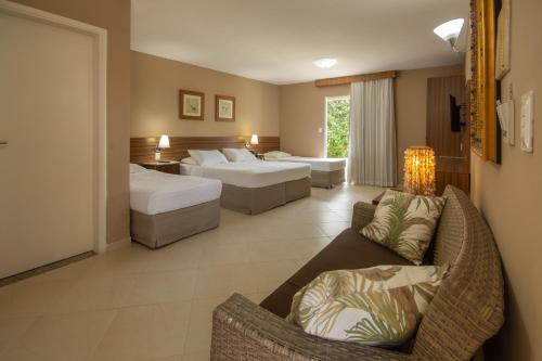 a hotel room with two beds and a couch at Hotel Coral Beach in Tamandaré
