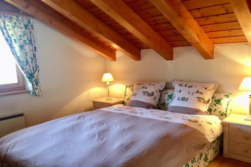 een slaapkamer met een groot bed in een kamer met houten plafonds bij Drive Combles in Bagnes