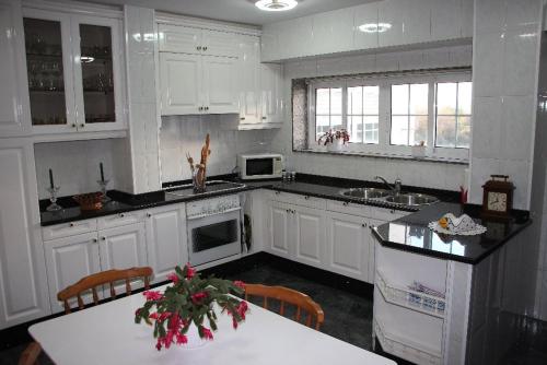 a kitchen with white cabinets and a table with a counter at El piso de Manuela VUT-CO-004057 in Padrón