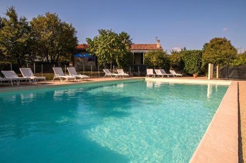 a large swimming pool with lounge chairs at Hôtel Les Persèdes in Lavilledieu