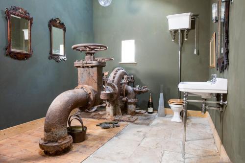 a bathroom with an old piping in a room with a sink at Cragend Grange in Rothbury