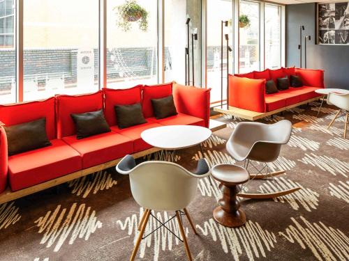 a living room with a red couch and chairs at ibis London Heathrow Airport in Hillingdon