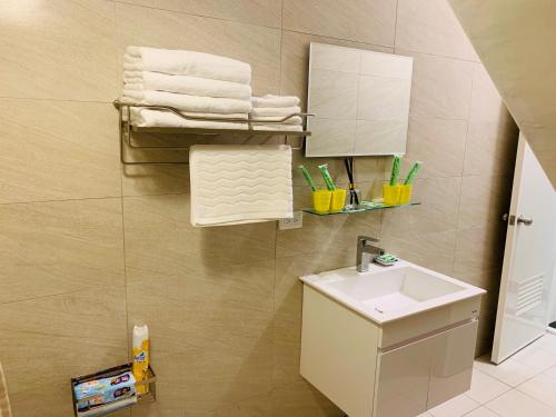 a bathroom with a sink and a mirror and towels at Xiang Quie B&B in Taitung City