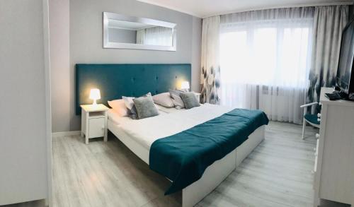 a bedroom with a large bed with a blue headboard at Apartament 44m2 w centrum in Tuchola