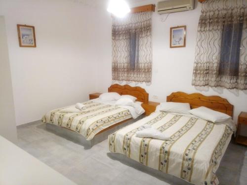 two beds in a room with white walls and windows at Hotel Perissa in Perissa