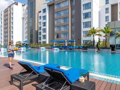 a woman standing next to a swimming pool in a hotel at Novotel Yangon Max in Yangon