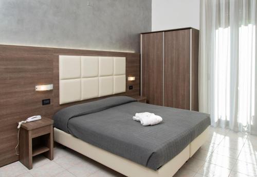 a bedroom with a large bed with a wooden headboard at Hotel Villa Luigia in Rimini