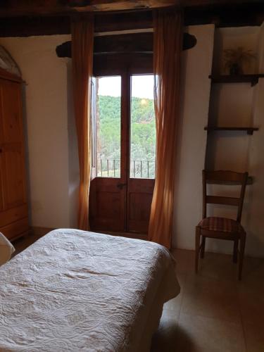 a bedroom with a bed and a window and a chair at Masia l`Arà in La Baronia de Rialb