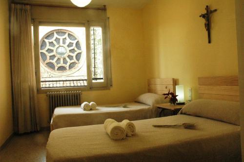 a bedroom with two beds and a window with a cross at Casa i Colla in Gironella