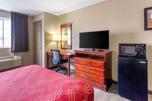 a hotel room with a bed and a tv and a desk at Econo Lodge Inn & Suites Dickson in Dickson