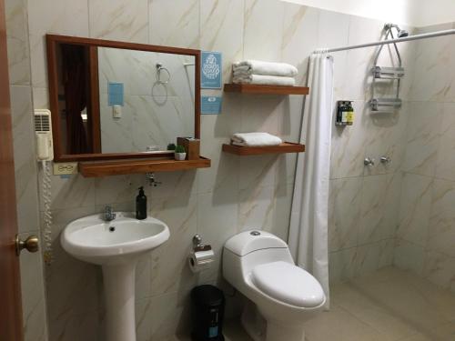 Un baño con lavabo, inodoro y espejo. en New Galapagos Hostelling, en Puerto Ayora