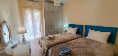 a bedroom with two beds and a lamp and a window at La casa di Eleni in Acharavi