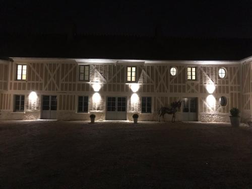 a white building with a horse in front of it at night at Domaine du Plessis in Le Plessis-Luzarches