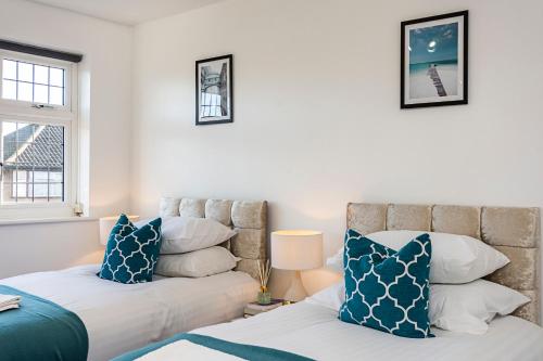a bedroom with two beds with blue and white pillows at Cozy 3 Bedroom House in Aveley, Thurrock in Aveley