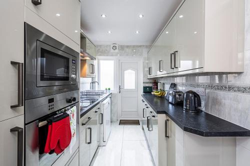 a large kitchen with white cabinets and black counter tops at Cozy 3 Bedroom House in Aveley, Thurrock in Aveley