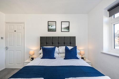 a bedroom with a large bed with blue pillows at Cozy 3 Bedroom House in Aveley, Thurrock in Aveley