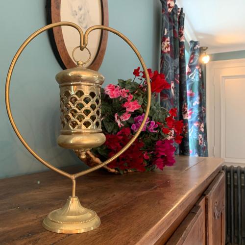 a gold lamp on a table with a vase of flowers at Domaine du Plessis in Le Plessis-Luzarches