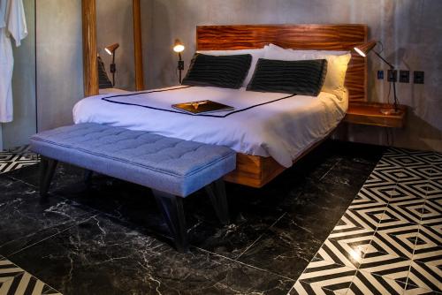 a bedroom with a large bed with a blue bench at Diez Diez Collection in Mérida